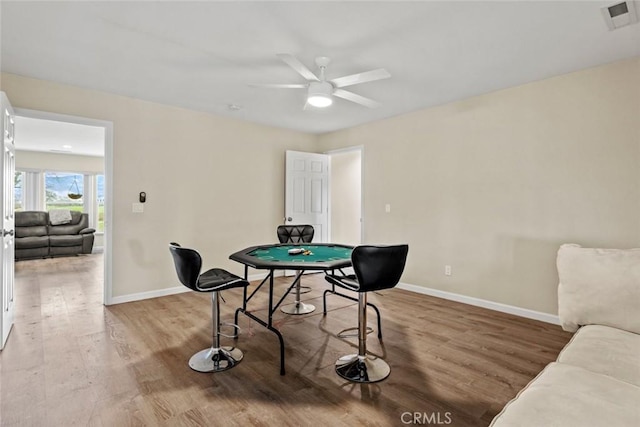 game room with a ceiling fan, wood finished floors, visible vents, and baseboards