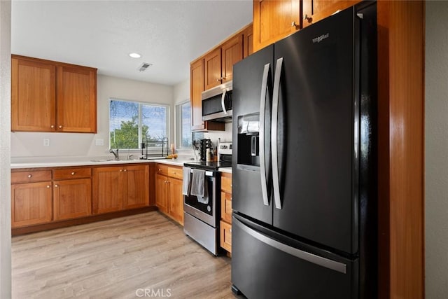 kitchen with visible vents, light countertops, light wood-style flooring, stainless steel appliances, and a sink