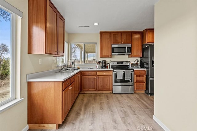 kitchen featuring visible vents, brown cabinets, stainless steel appliances, and a sink