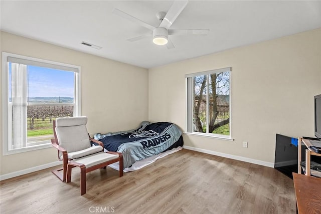 bedroom featuring visible vents, multiple windows, wood finished floors, and baseboards