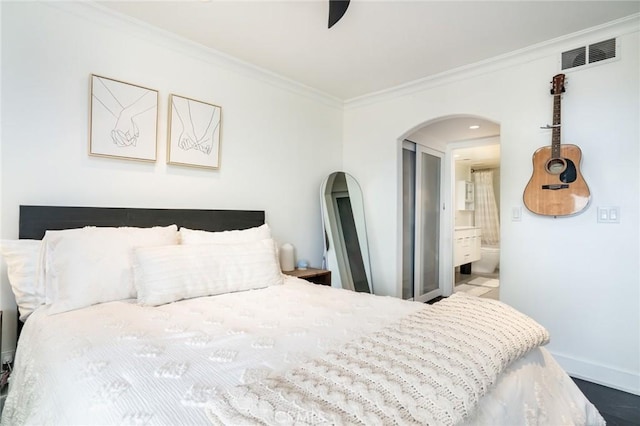 bedroom with baseboards, visible vents, ensuite bath, arched walkways, and ornamental molding