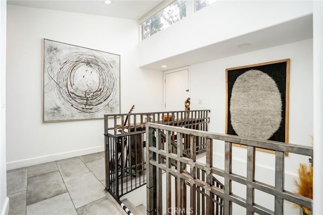 hall featuring baseboards, a high ceiling, recessed lighting, tile patterned flooring, and an upstairs landing