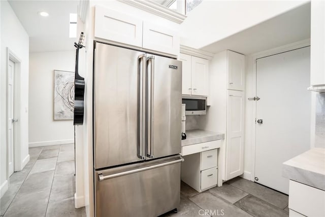 kitchen featuring light tile patterned flooring, recessed lighting, light countertops, appliances with stainless steel finishes, and white cabinetry