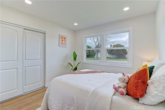 bedroom with recessed lighting, a closet, and light wood-style flooring