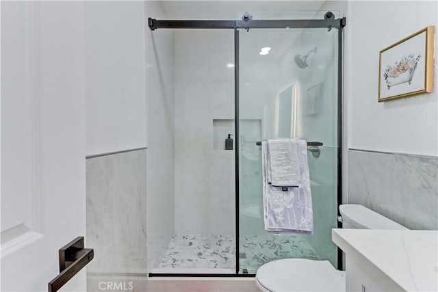 bathroom featuring tile walls, a stall shower, toilet, and vanity