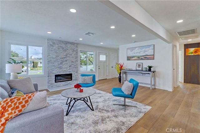 living area with visible vents, recessed lighting, a stone fireplace, and light wood-style floors