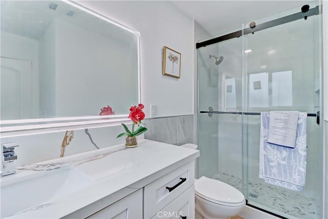 full bath featuring vanity, wainscoting, a shower stall, and toilet