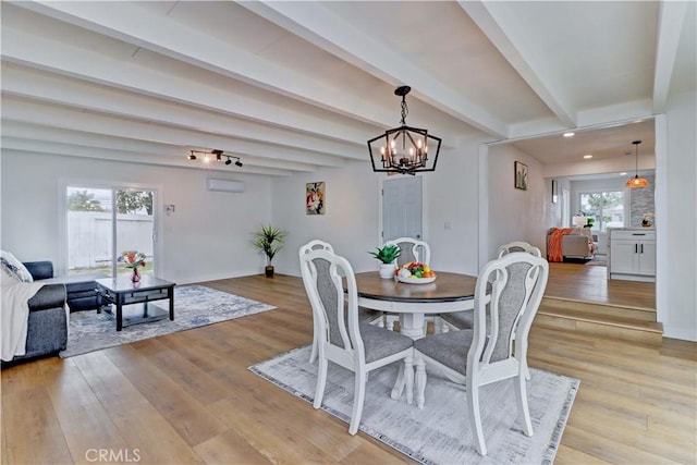 dining area with an inviting chandelier, beam ceiling, and light wood finished floors