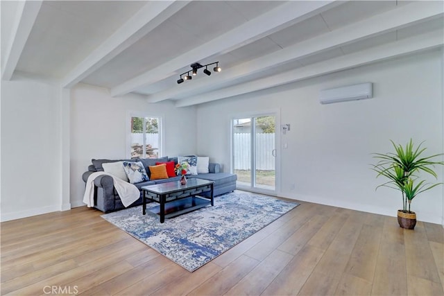 living room with beam ceiling, an AC wall unit, baseboards, and wood finished floors