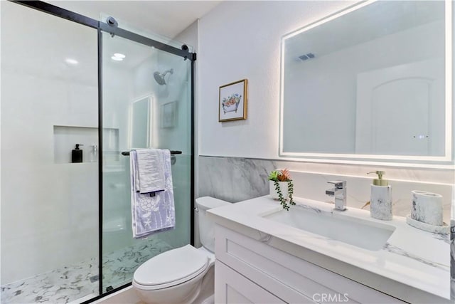 bathroom with vanity, visible vents, a shower stall, tile walls, and toilet