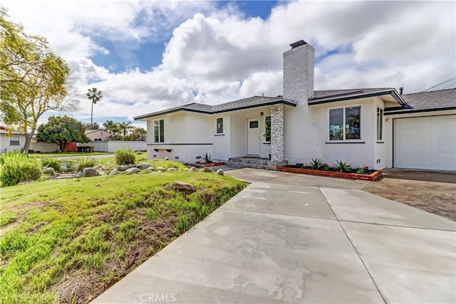 prairie-style house featuring stucco siding, driveway, a front yard, a garage, and a chimney