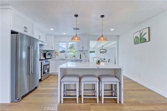 kitchen featuring visible vents, under cabinet range hood, light countertops, white cabinets, and stainless steel appliances