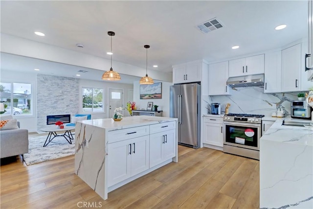 kitchen featuring visible vents, under cabinet range hood, open floor plan, light wood-style floors, and stainless steel appliances