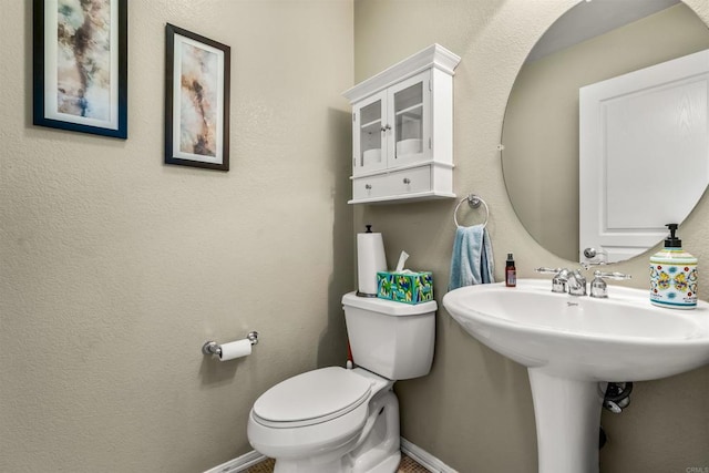 half bath featuring a sink, baseboards, and toilet