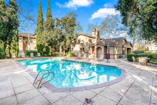 pool with a patio area, central air condition unit, a residential view, and fence