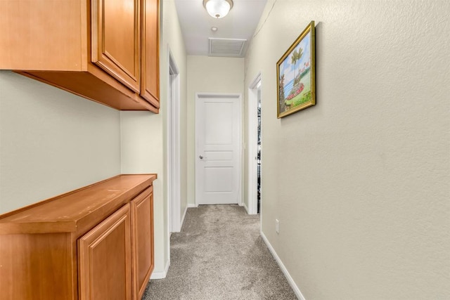 corridor featuring baseboards, visible vents, and light carpet