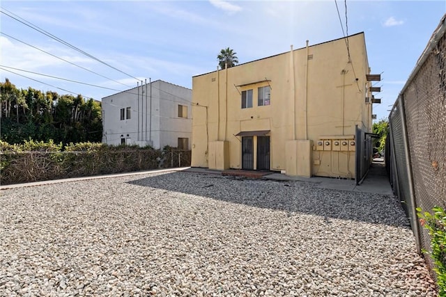 back of property featuring stucco siding and fence