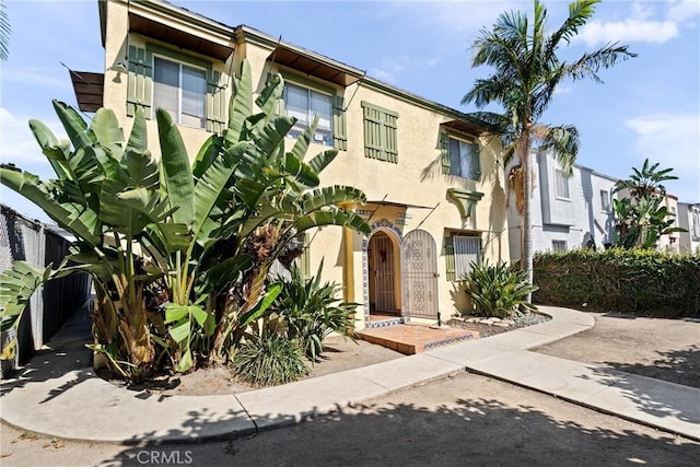 townhome / multi-family property with stucco siding, fence, and a gate