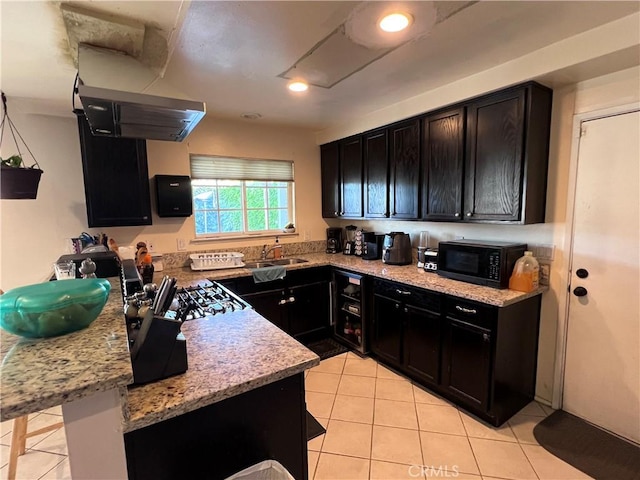 kitchen with light tile patterned flooring, dark cabinets, black microwave, and a sink