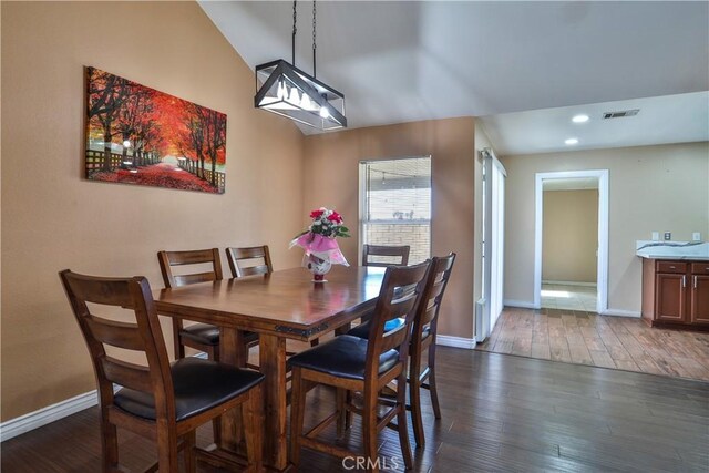 dining area with visible vents, baseboards, dark wood-style flooring, and vaulted ceiling