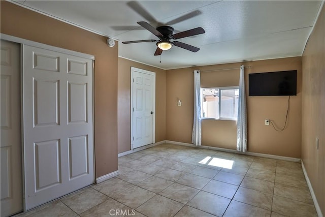 unfurnished bedroom with baseboards, light tile patterned flooring, and a ceiling fan