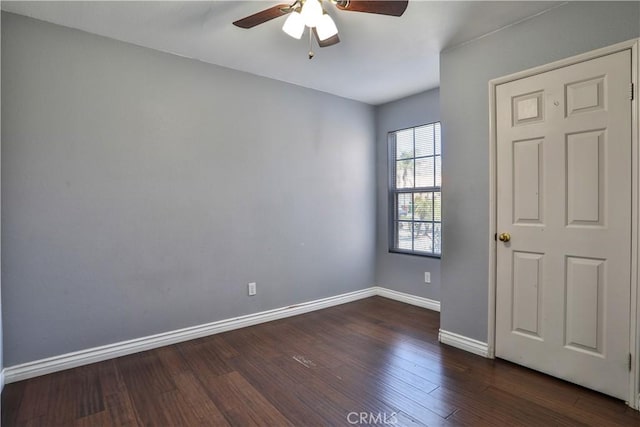 empty room with dark wood finished floors, ceiling fan, and baseboards