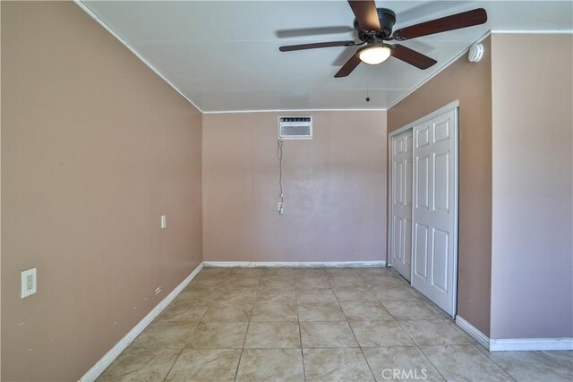 unfurnished bedroom with a closet, baseboards, an AC wall unit, and a ceiling fan