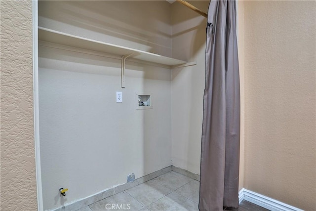 laundry room with a textured wall, washer hookup, laundry area, and tile patterned flooring