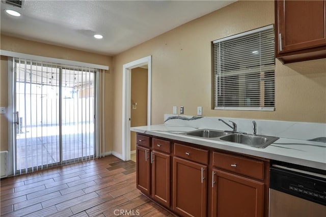 kitchen featuring a sink, stainless steel dishwasher, wood tiled floor, and light countertops