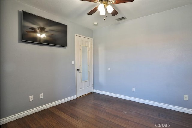 spare room featuring visible vents, baseboards, a ceiling fan, and dark wood-style flooring