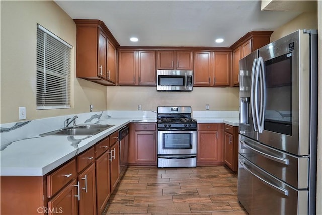 kitchen with wood finish floors, a sink, recessed lighting, appliances with stainless steel finishes, and light countertops