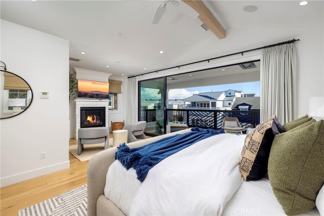 bedroom featuring wood finished floors, baseboards, vaulted ceiling with beams, access to exterior, and a glass covered fireplace