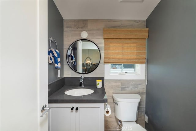 half bathroom with tile walls, toilet, and vanity