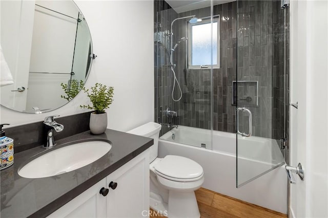 full bath with vanity, toilet, wood finished floors, and combined bath / shower with glass door