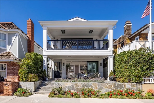 view of front of property featuring a balcony, brick siding, and a patio area