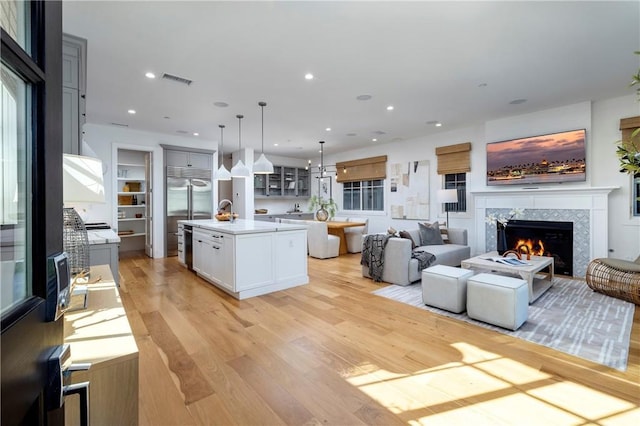 living room with recessed lighting, light wood-style flooring, a fireplace, and visible vents