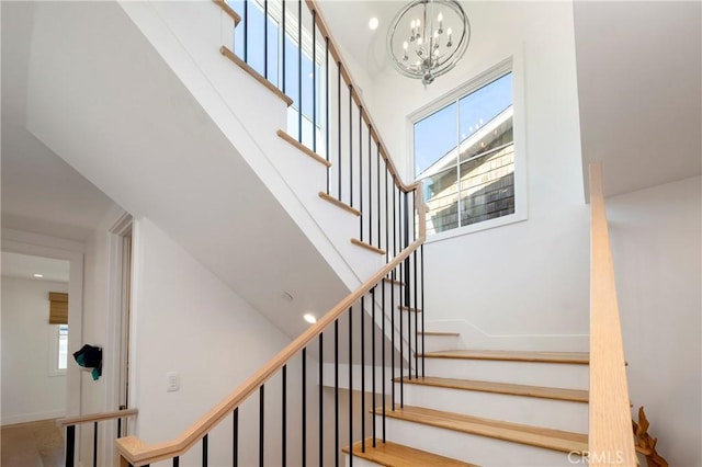 stairway featuring recessed lighting, baseboards, a towering ceiling, and a chandelier