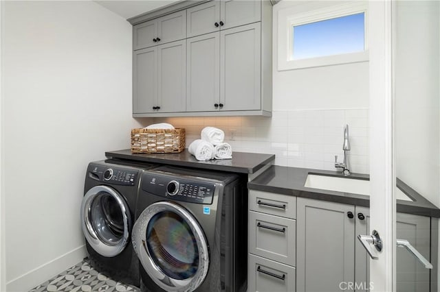 washroom featuring a sink, baseboards, cabinet space, and washing machine and clothes dryer