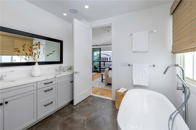 ensuite bathroom with a sink, a soaking tub, ensuite bath, and double vanity