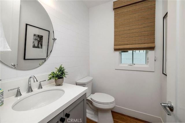 half bathroom featuring baseboards, toilet, and vanity