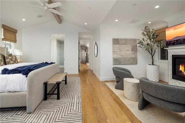 bedroom featuring baseboards, a premium fireplace, lofted ceiling with beams, recessed lighting, and light wood-style floors