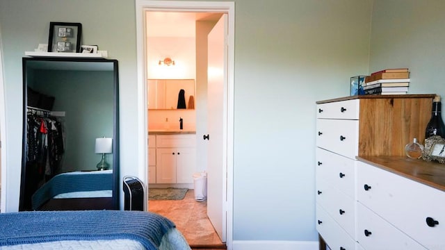 bedroom featuring a sink, light tile patterned flooring, and ensuite bathroom