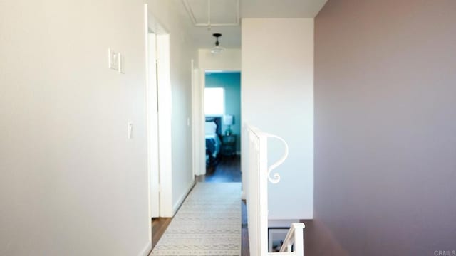 hallway with attic access and wood finished floors