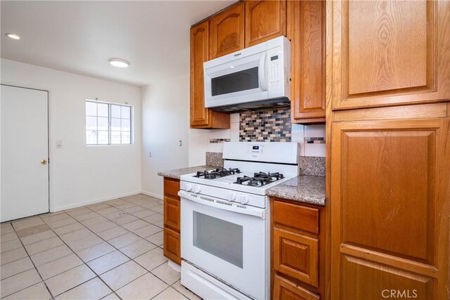 kitchen featuring white appliances, backsplash, light tile patterned flooring, and brown cabinetry