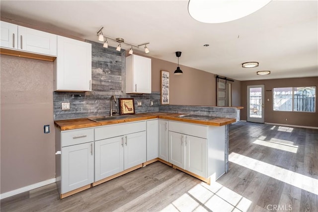 kitchen featuring a sink, tasteful backsplash, open floor plan, a barn door, and a peninsula