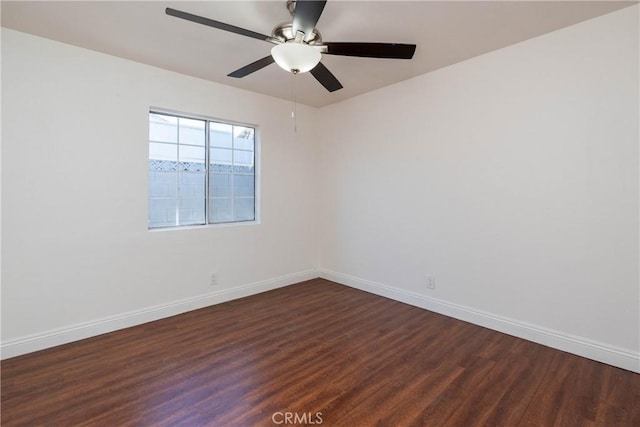 empty room featuring a ceiling fan, dark wood-style floors, and baseboards