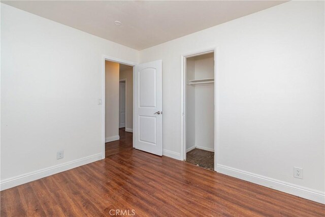 unfurnished bedroom with a closet, baseboards, and wood finished floors