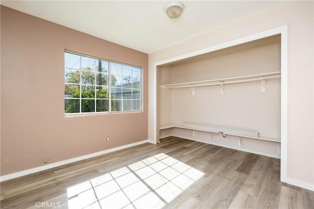 unfurnished bedroom with a closet, baseboards, and wood finished floors