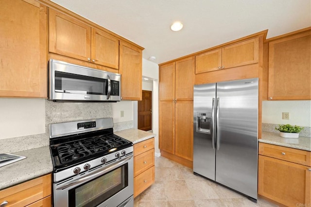 kitchen featuring light stone counters, backsplash, and stainless steel appliances