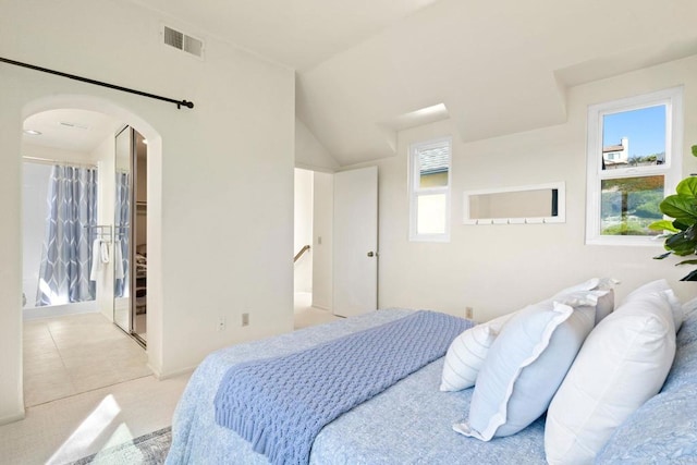 bedroom featuring arched walkways, visible vents, light tile patterned flooring, and vaulted ceiling